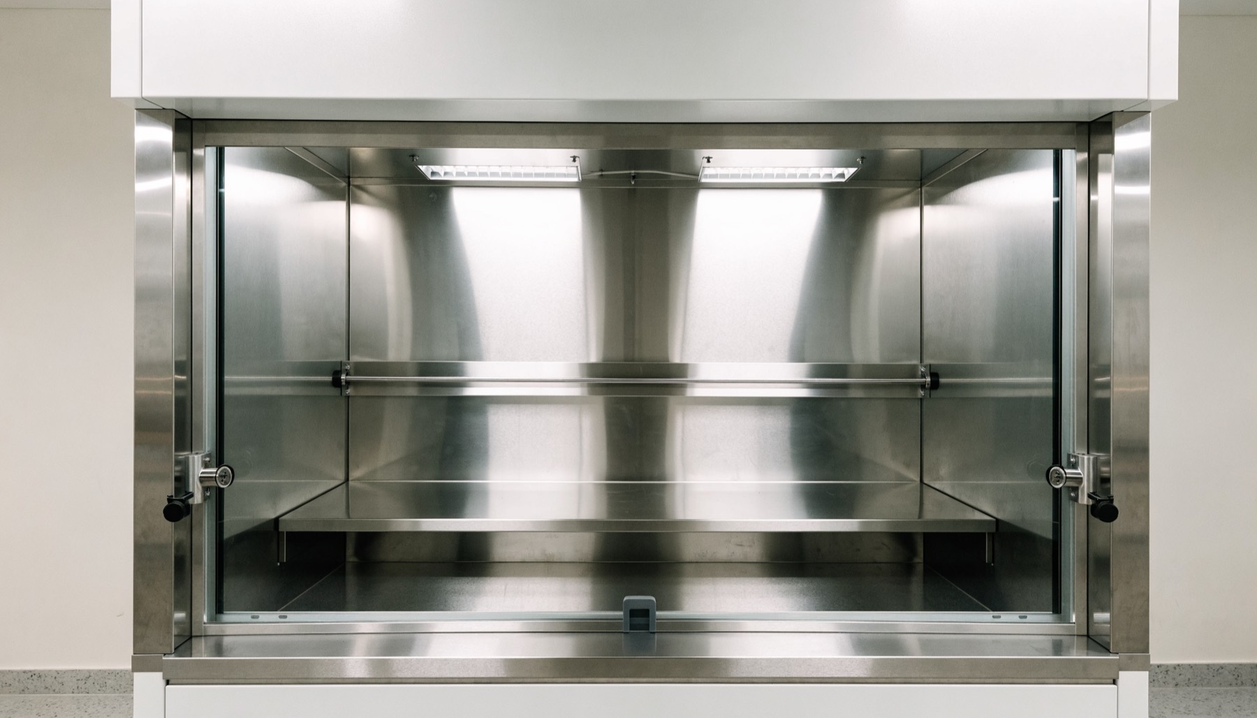 An empty stainless steel fume cupboard with the glass sash half lowered